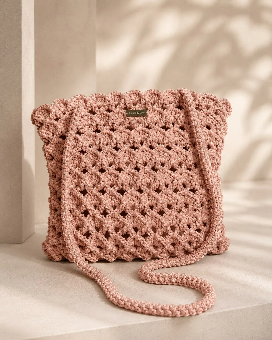 Dusty rose crochet shoulder bag in an open granny stitch with a scalloped edge and a long slim crocheted strap