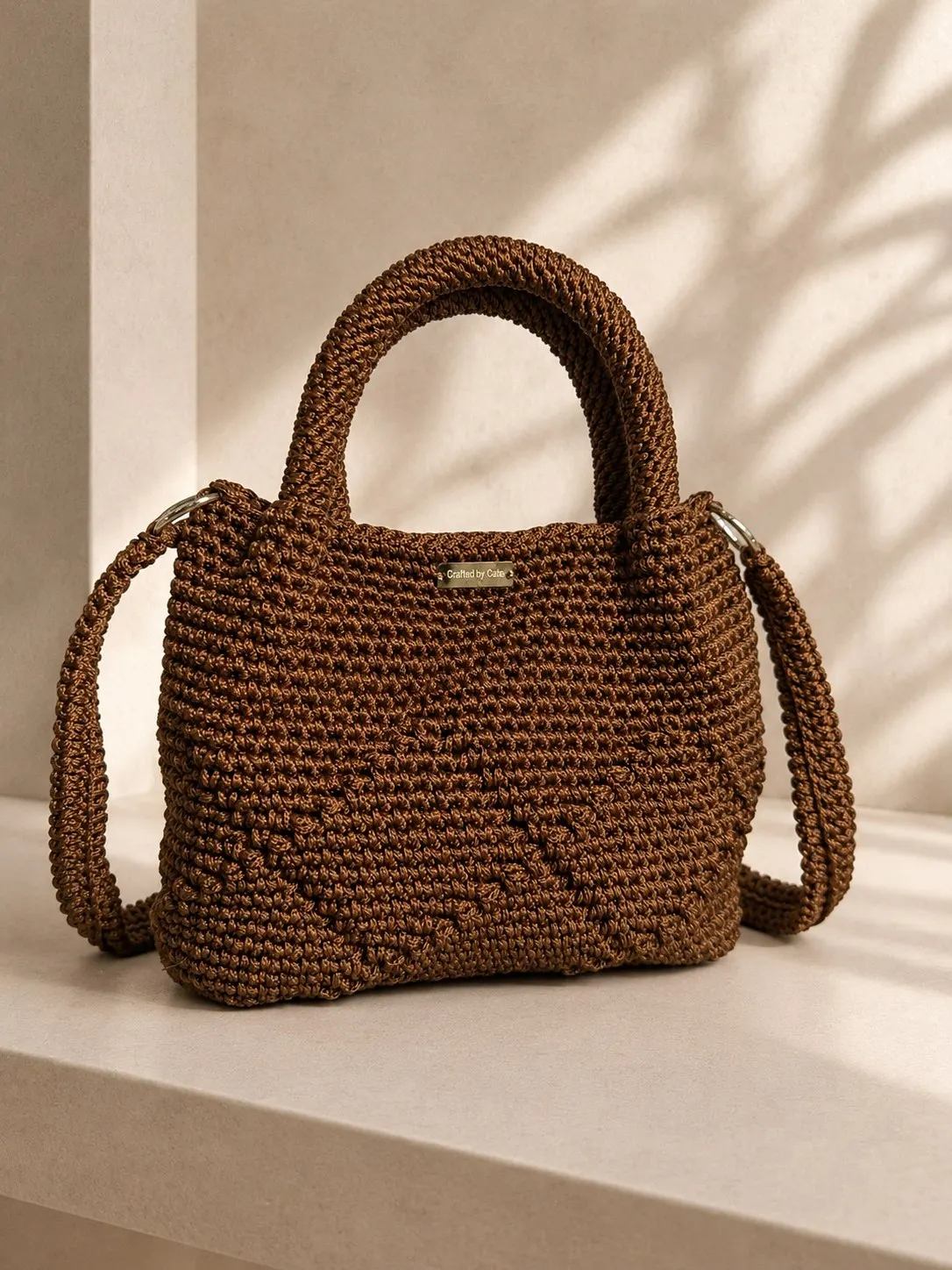 Chestnut brown textured crochet handbag with short top handles and a long detachable crossbody strap