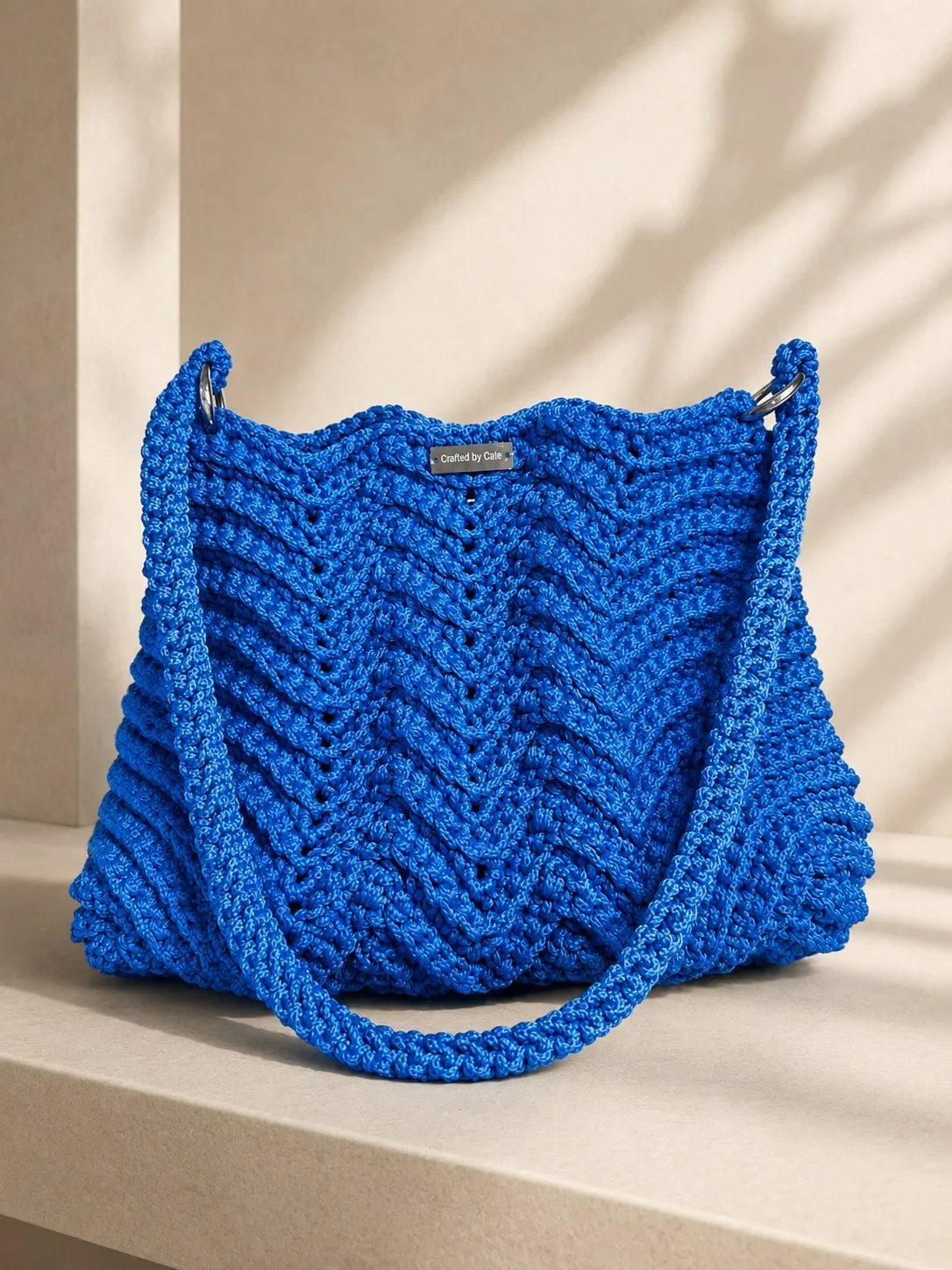Cobalt blue crochet tote worked in a rippling chevron stitch with the shoulder strap set on silver metal rings